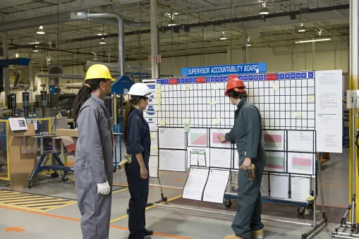 Plant floor operator reviewing a WIP priority board in a high-mix, low-volume manufacturing cell.