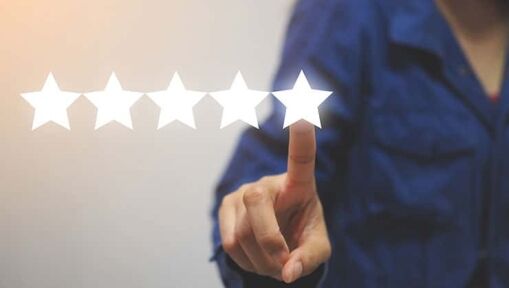A person in a blue shirt is pointing at the fifth star in a row of five glowing stars, suggesting a five-star rating or review. The background is plain and out of focus.